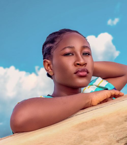 Free Portrait of a woman with a serene expression against a vibrant blue sky with clouds. Stock Photo