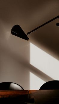 Sophisticated black lamp casting dramatic shadows on a minimalist wall.