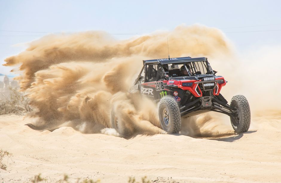 Exciting rally vehicle navigating the sandy terrain of Ensenada, Mexico, at high speed.