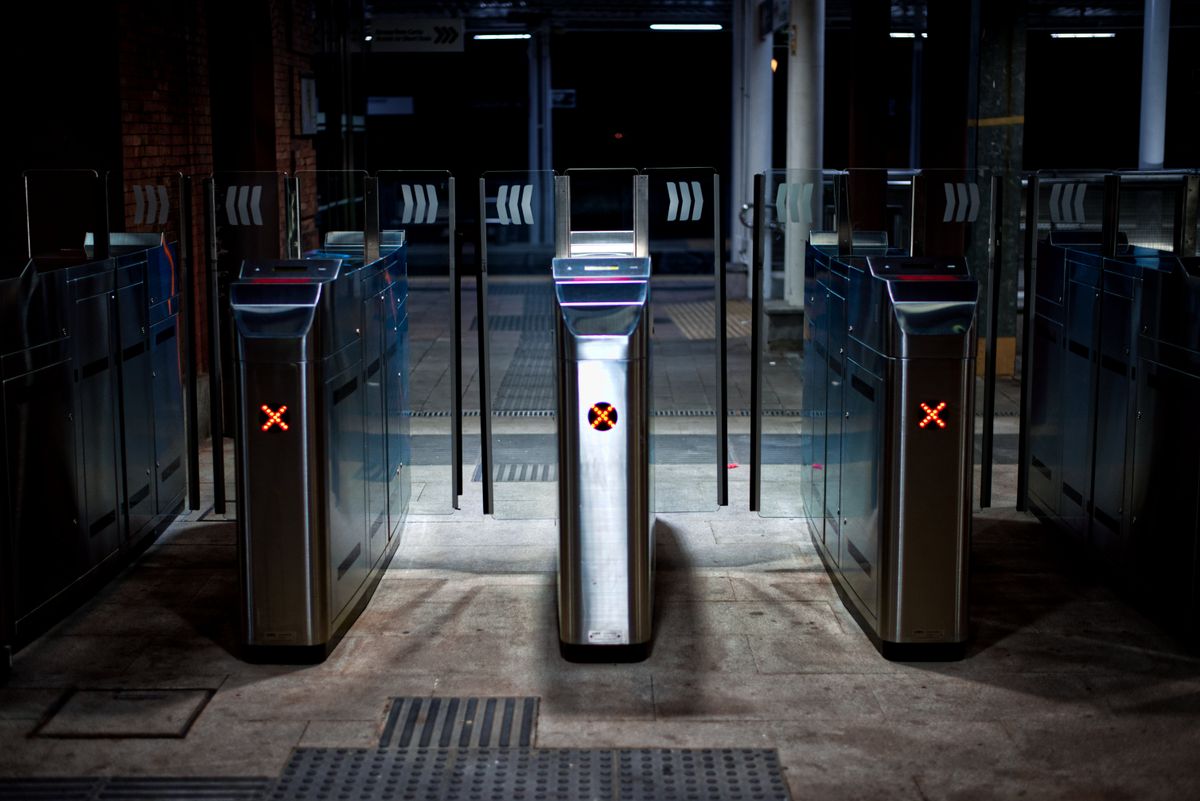 Three empty ticket barriers at night, each showing a red X.