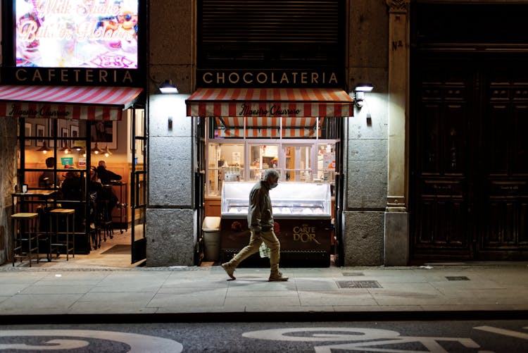 An Elderly Man Walking In Front Of A Restaurant