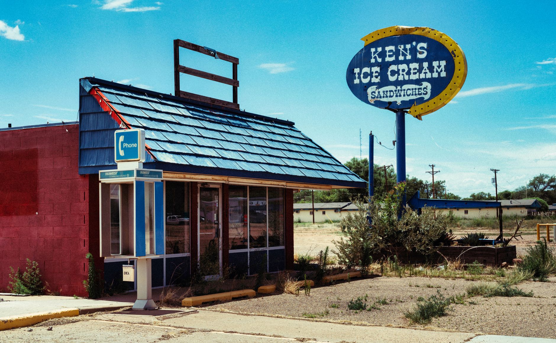 Retro style abandoned ice cream shop with a classic phone booth under a bright summer sky.