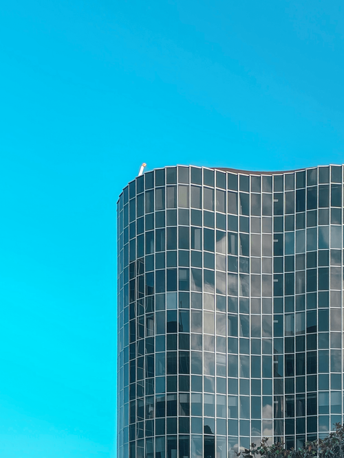 Free Tall modern glass skyscraper with reflection against a vibrant blue sky in Barcelona, Spain. Stock Photo