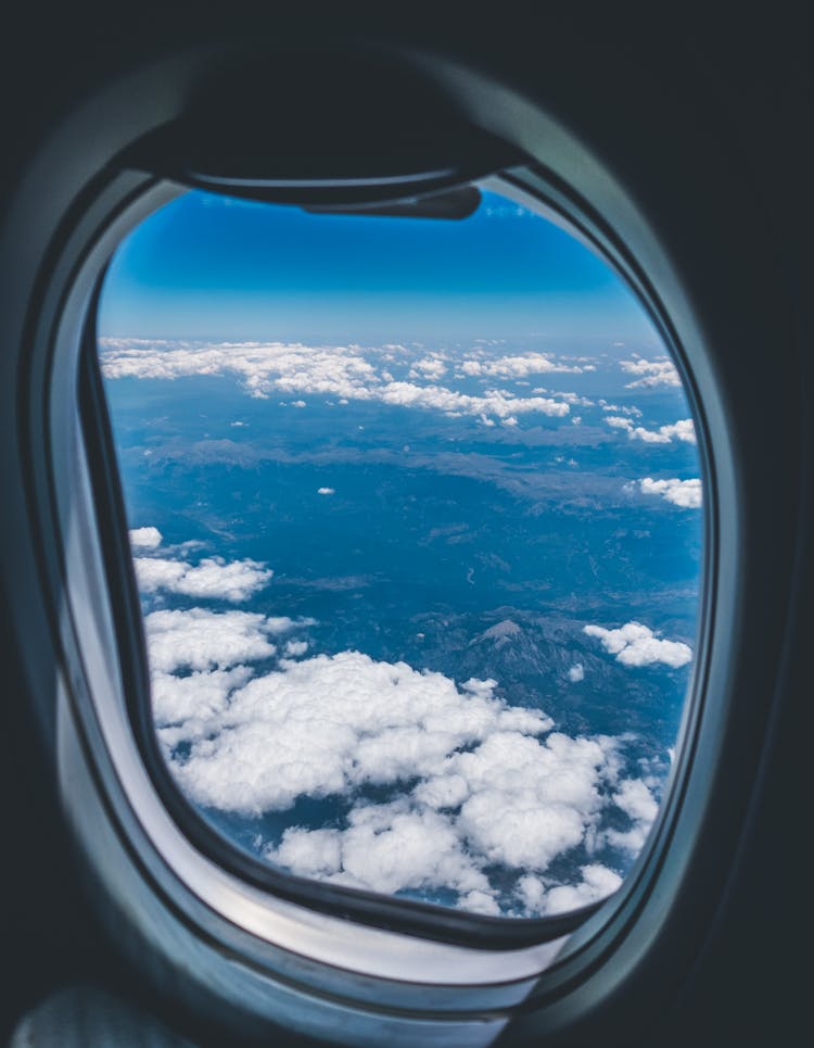 Airplane Window View Of White Clouds Over Mountain