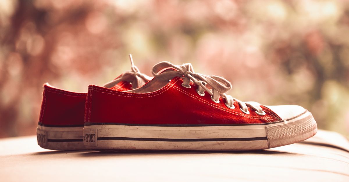 Stylish red canvas sneakers with white laces shown in a classic side view.