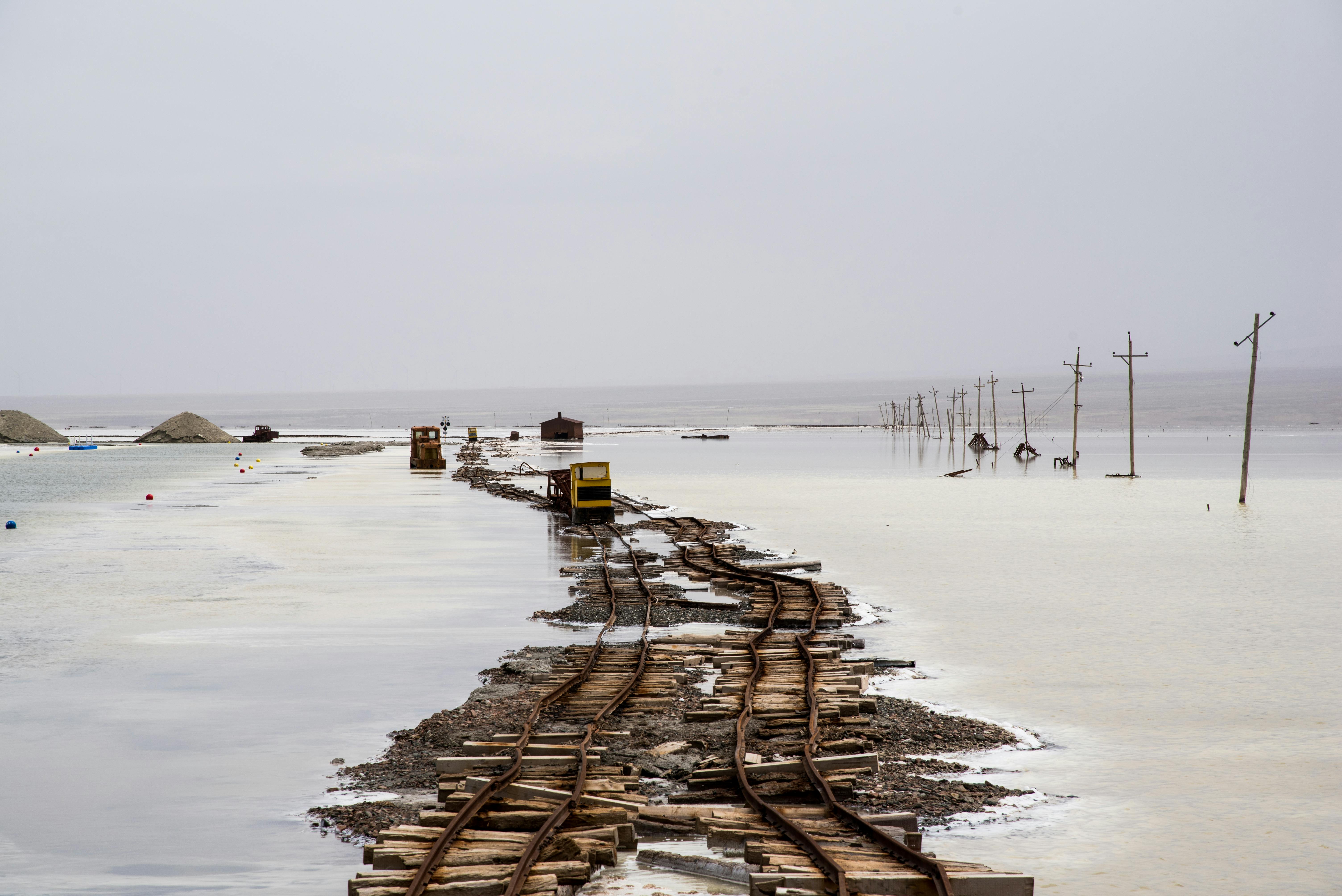 Desolate scene of abandoned railway tracks submerged in water on an overcast day.