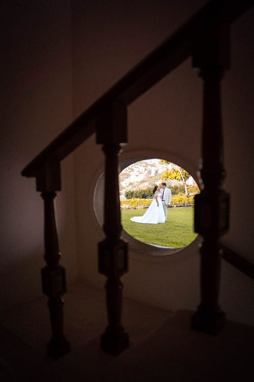Bride and Groom Standing Outside Photographed Through a Window 