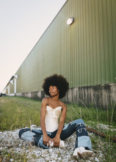 Stylish young woman sitting outside with afro hairstyle in Des Moines, IA.