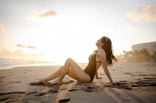 Brunette in Swimming Costume Sitting on Beach