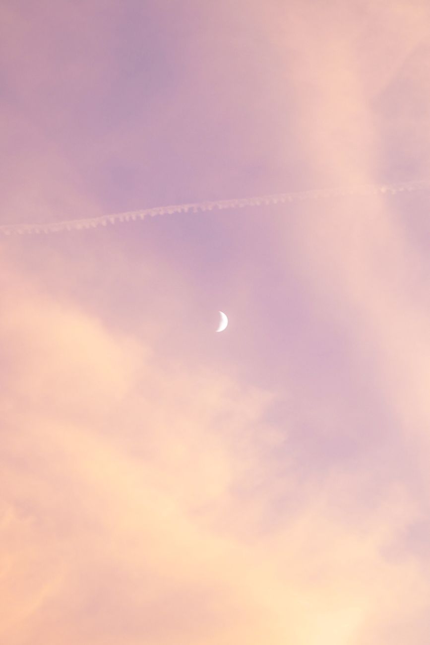 A crescent moon in a pastel pink and purple sky over Chicago during sunset.