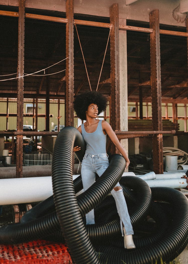 Fashion Girl In Jeans And White High Heels Posing With Black Pipes