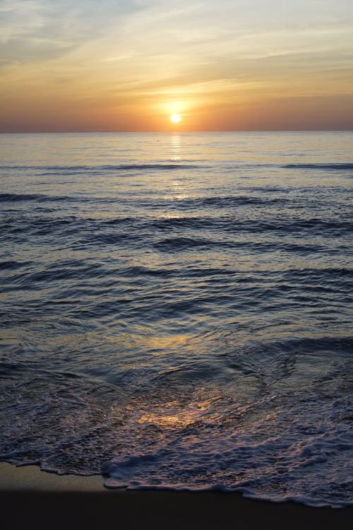 Free Calm sea waves under a vibrant sunrise, creating a peaceful ocean horizon view. Stock Photo