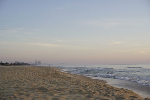 Free A tranquil beach scene with gentle waves and a clear morning sky, perfect for relaxation. Stock Photo