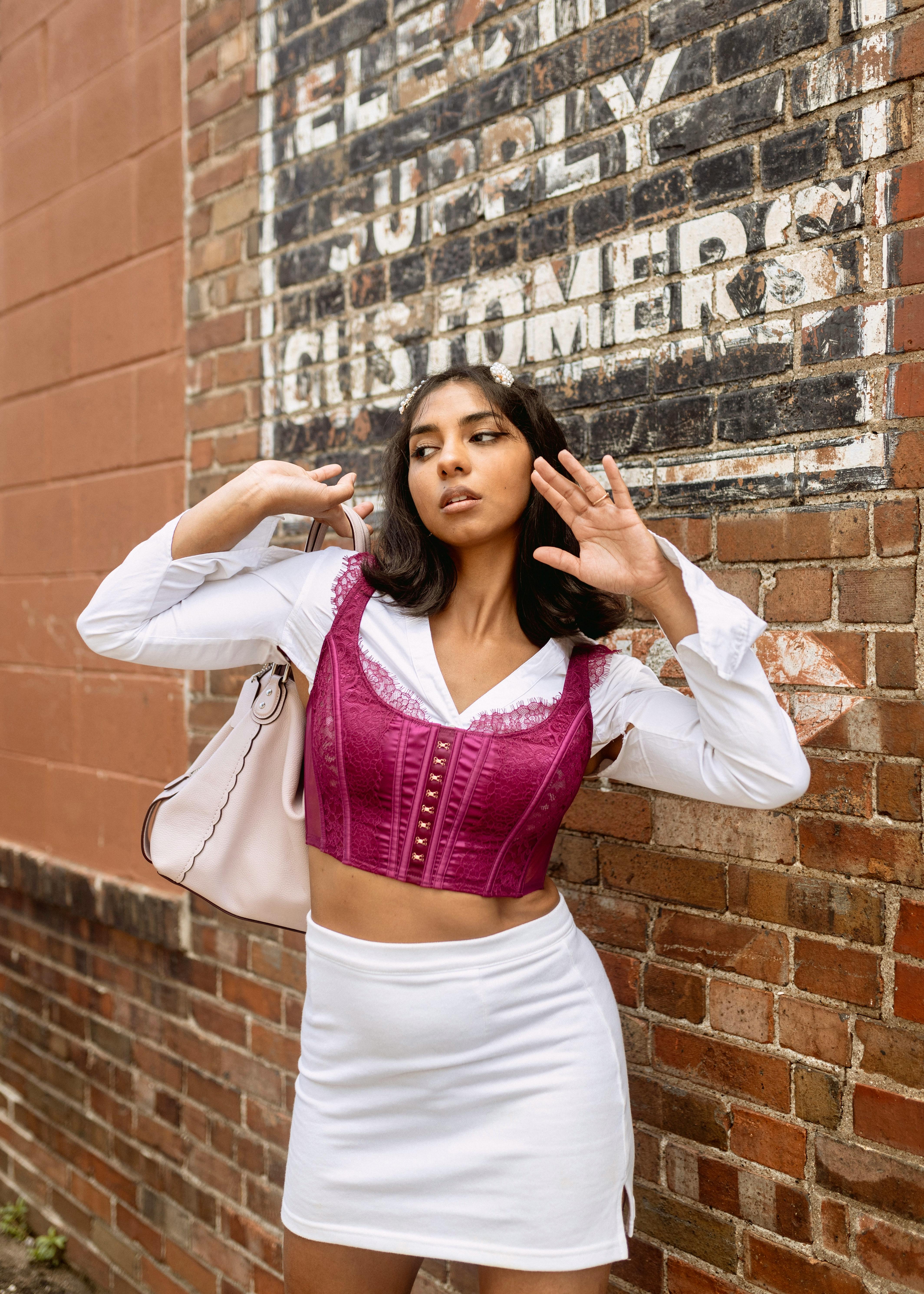 Stylish woman poses confidently in urban Des Moines setting with vintage brick wall background.
