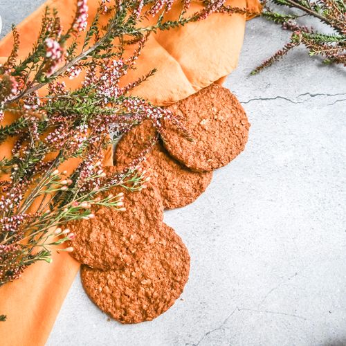Free Top view of oatmeal cookies on a rustic surface with floral accents, perfect for food photography. Stock Photo