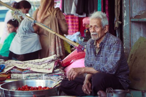 Free An elderly man selling textiles at a bustling market in Kashmir, India. Stock Photo