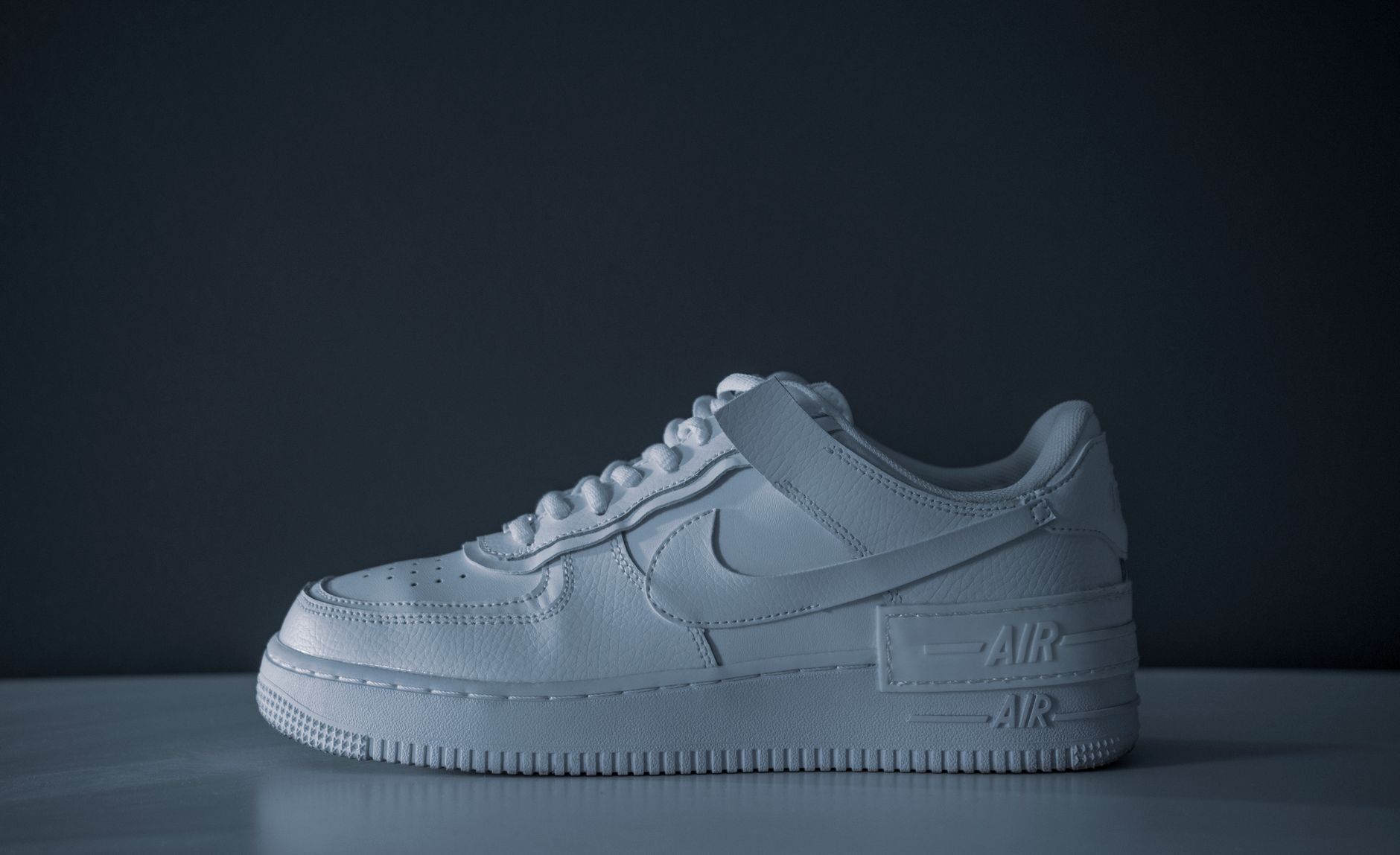 Minimalist image of a white sneaker on a dark background showcasing modern style.