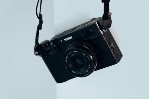 Free Detailed close-up of a vintage camera with black body and lens viewed from above on a light blue background. Stock Photo