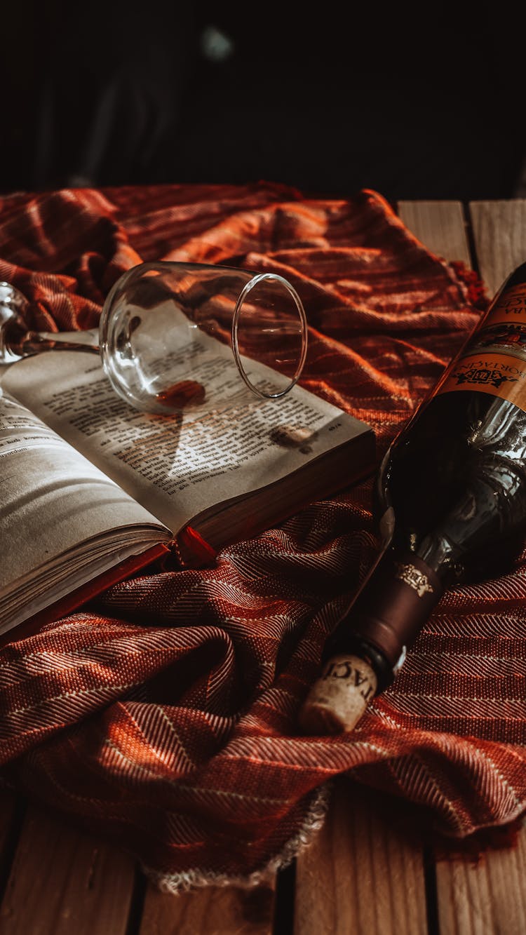 A Bottle Of Wine Beside An Open Book