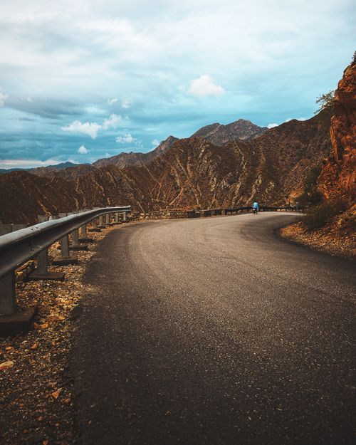 Free Scenic winding road through rocky Kohat mountains under cloudy sky, Khyber Pakhtunkhwa, Pakistan. Stock Photo