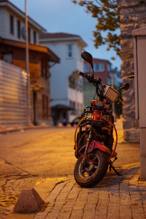 Free A solitary motorcycle parked on a cobblestone street in Istanbul at twilight, capturing the city's essence. Stock Photo