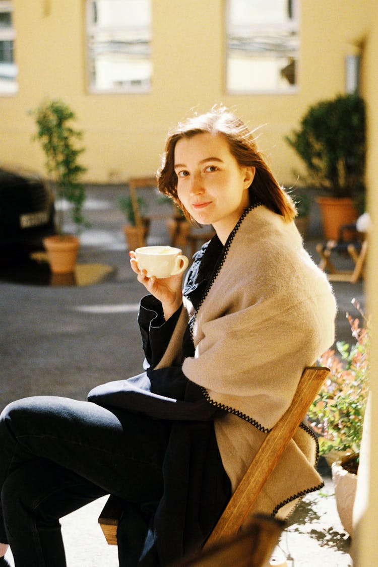 Young Woman Drinking Coffee In Cafe Outdoors