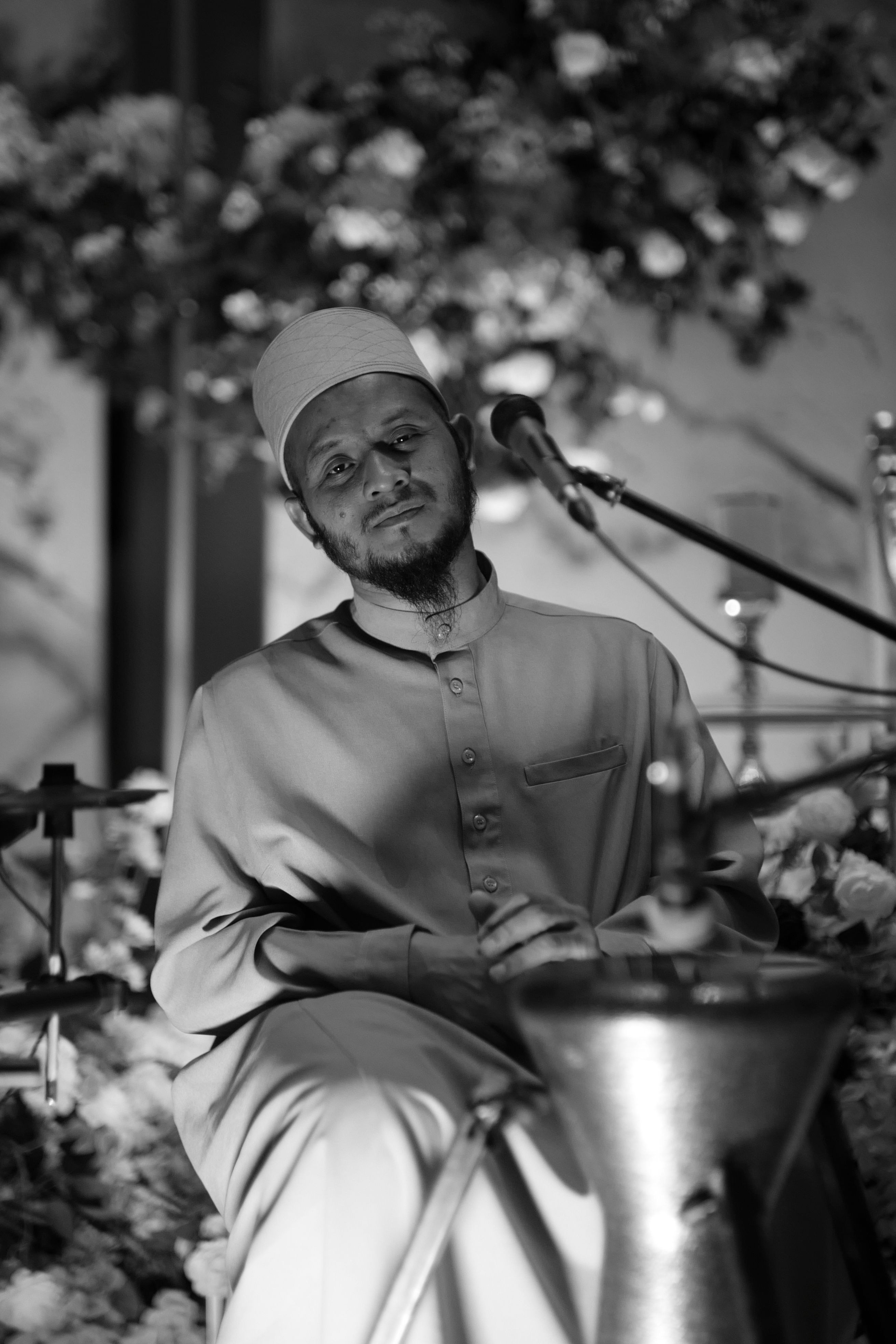 A monochrome portrait of a man with a microphone, capturing a reflective mood.