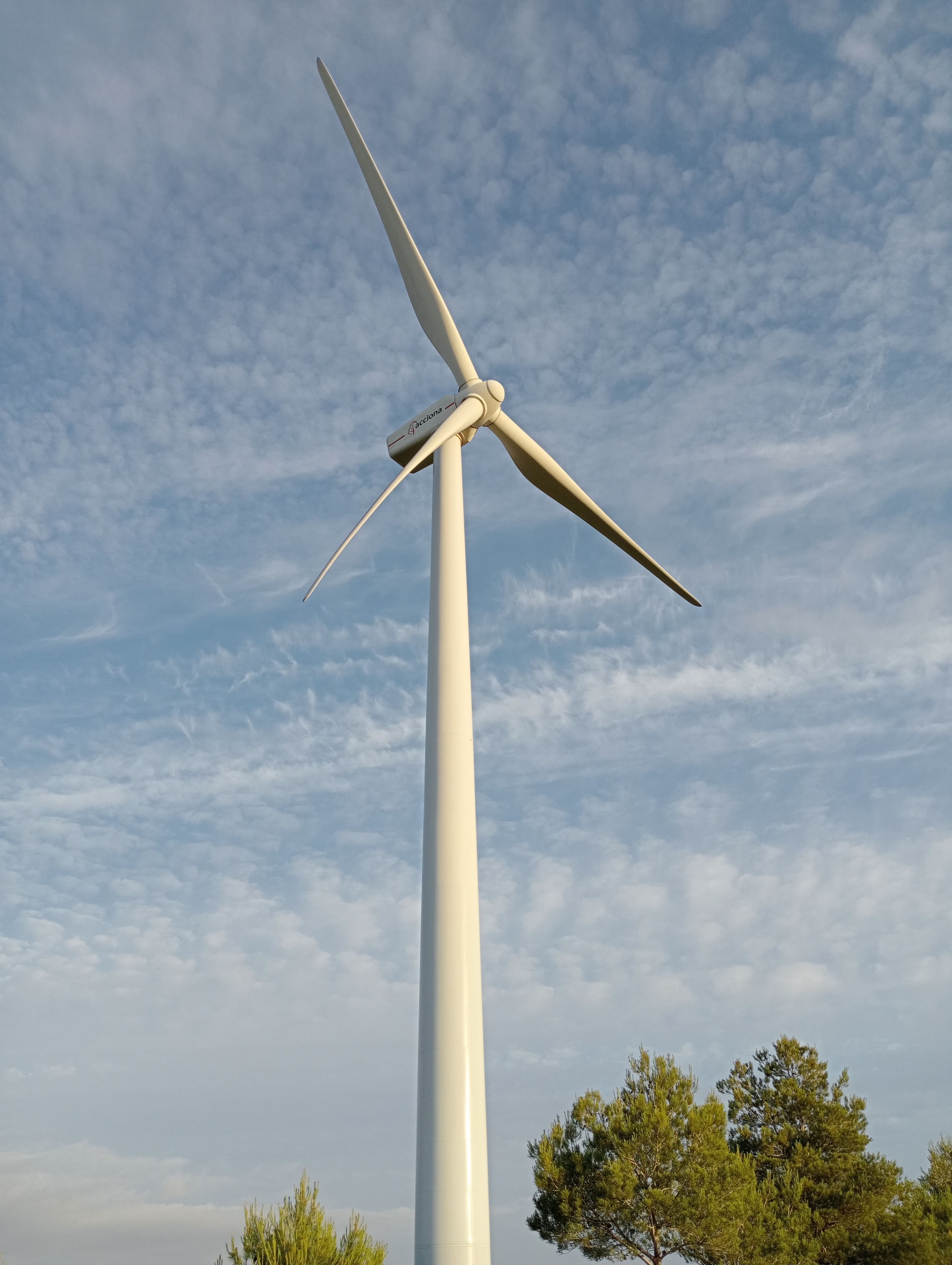 A Low Angle Shot of a Windmill Under the Blue Sky and White Clouds