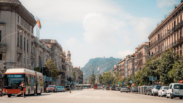 Lively urban street scene in Barcelona showcasing classic architecture and Montjuïc mountain in the backdrop.