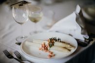 A gourmet asparagus plate with garnish on a table set for fine dining.