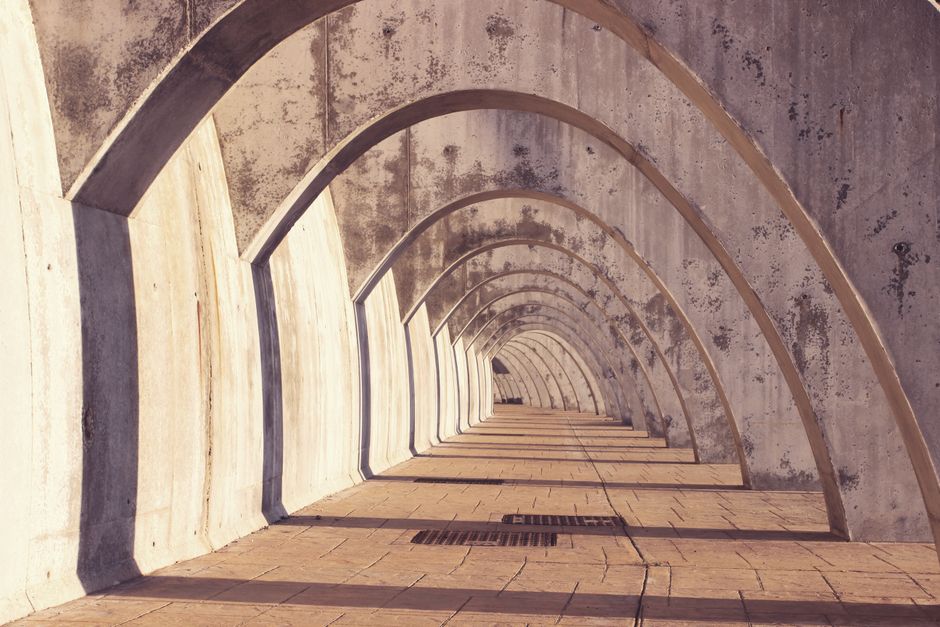 A minimalist arched concrete structure in Málaga, Spain casting long shadows