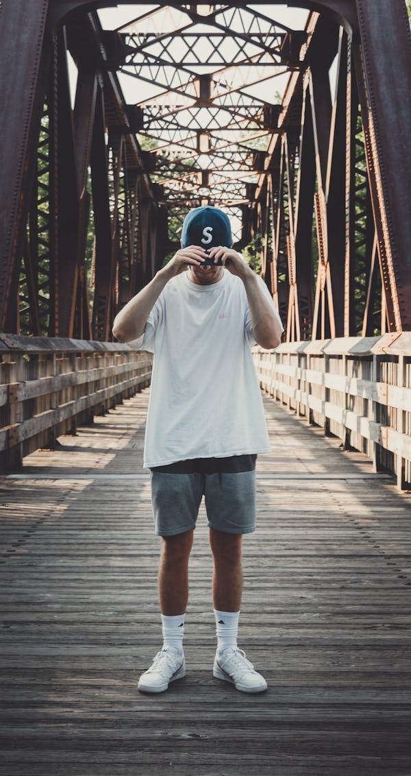 Man in White Crew-neck T-shirt Standing on Bridge