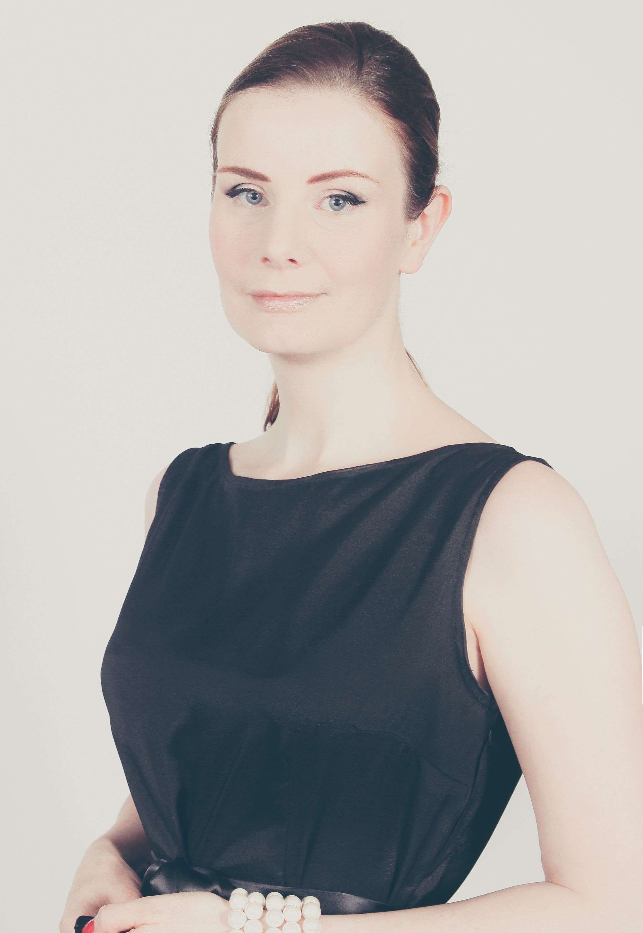 Beautiful portrait of a woman in a classic black dress with soft lighting and neutral background.