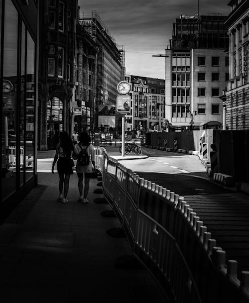 Grayscale Photo of Women Walking on a Sidewalk