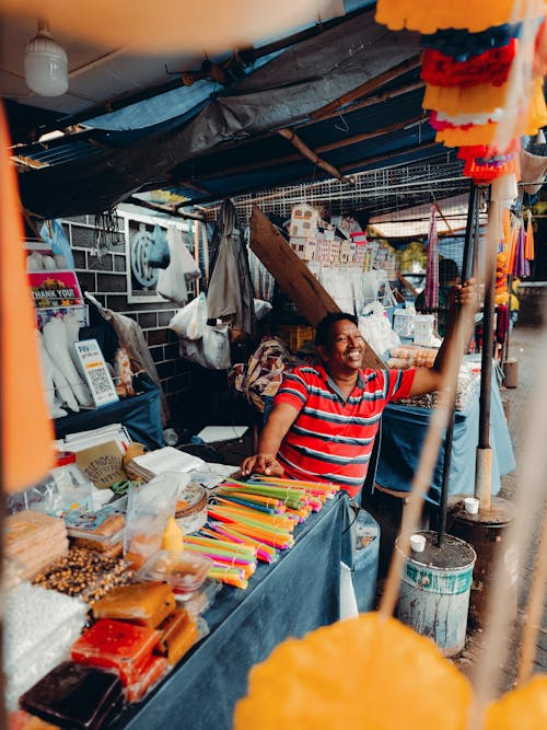 Man in Red and White Stripe Polo Shirt Selling Various Items