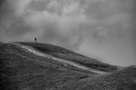 A lone figure stands atop a hill in the Tatry mountains, a perfect scene for adventure seekers.