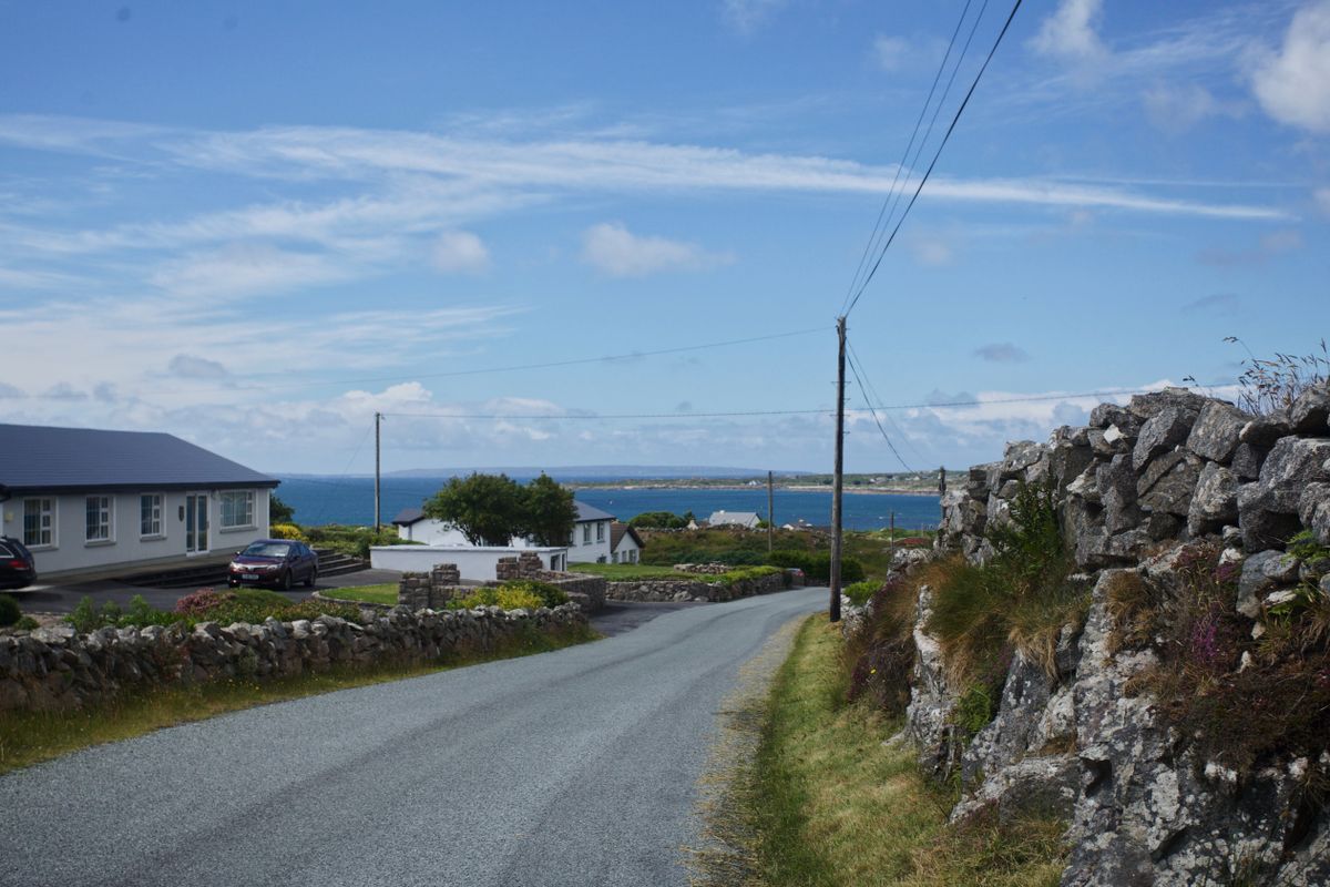 A narrow Irish coastal road lined with stone walls