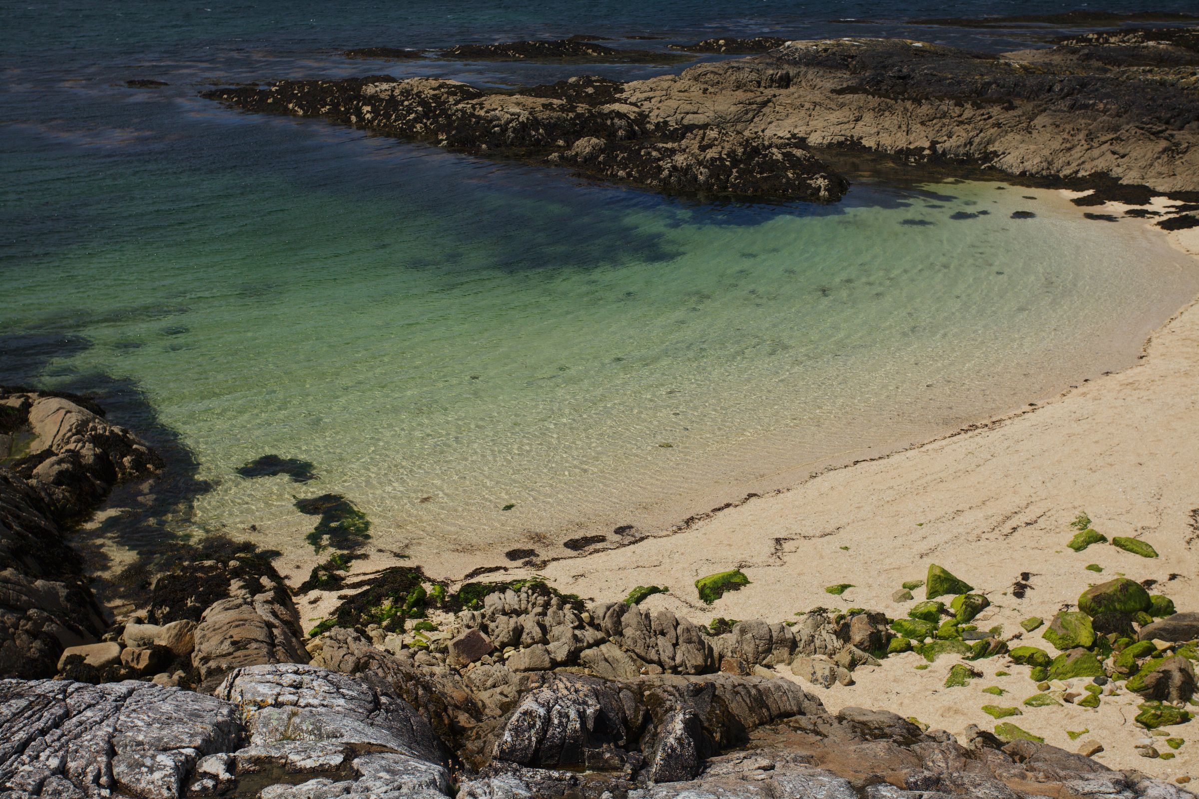 A Irish beach with clear turquoise water and rocky shoreline,