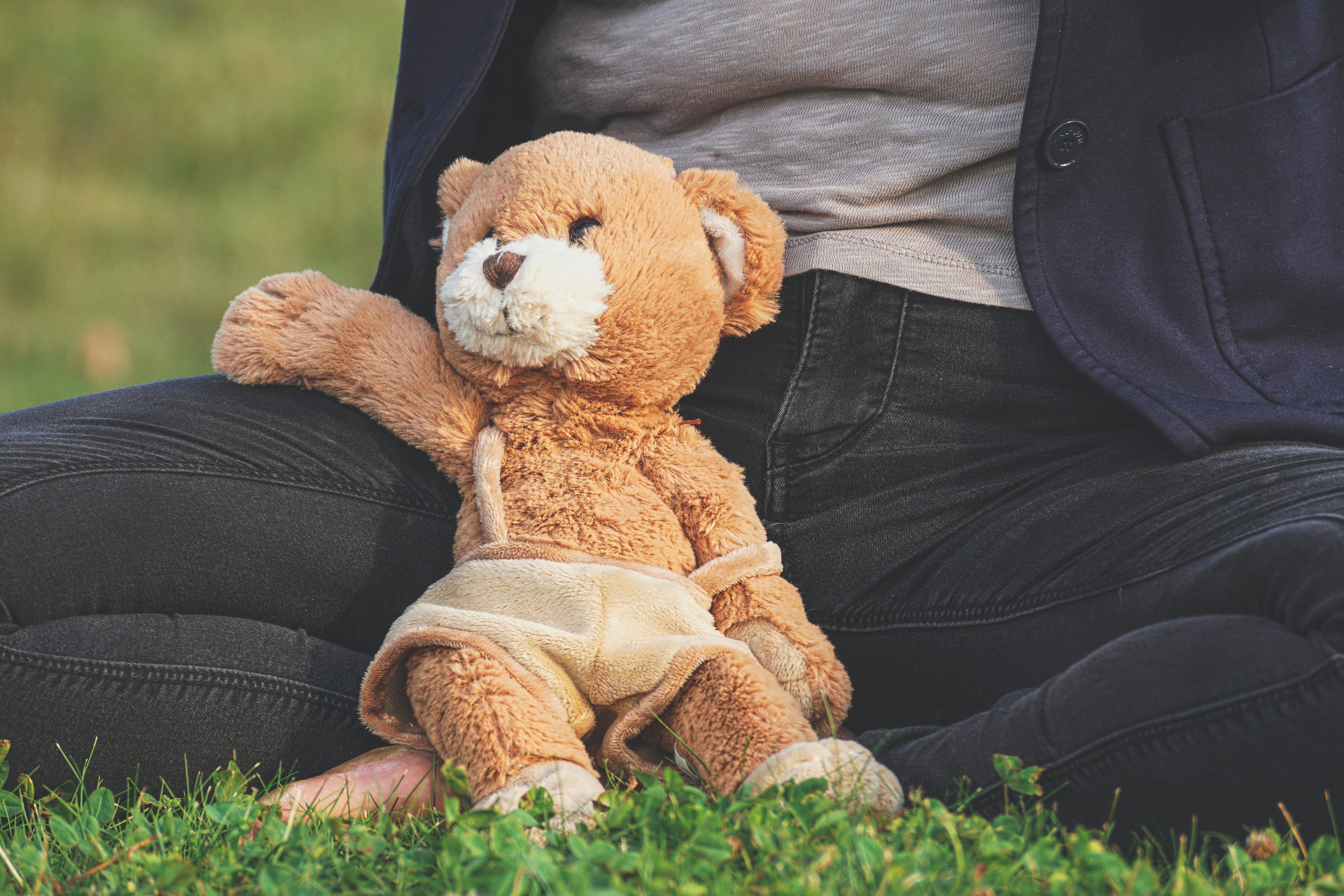 brown teddy bear toy leaning on person