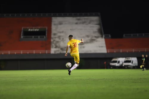Man in Yellow Soccer Jersey Playing Football on Football Field