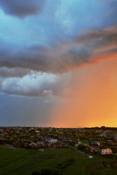A striking sunset with vibrant colors over a suburban neighborhood with cloudy sky.