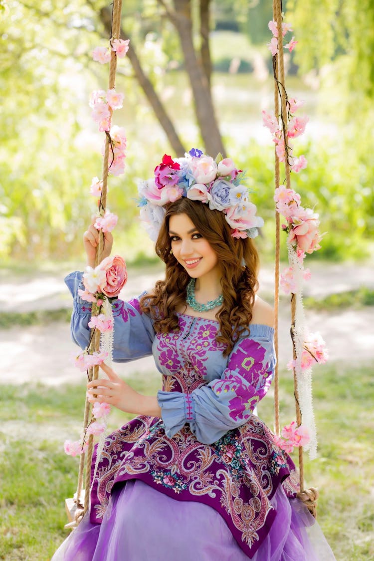 Girl In Purple And Pink Floral Dress Sitting On Swing