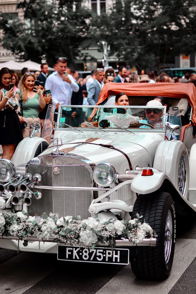 Couple Driving In A Vintage Car On Their Wedding Day 