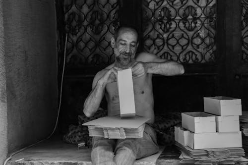 Grayscale Photo of a Man Making Boxes