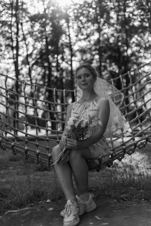 Grayscale Photo of Woman Sitting on a Hammock