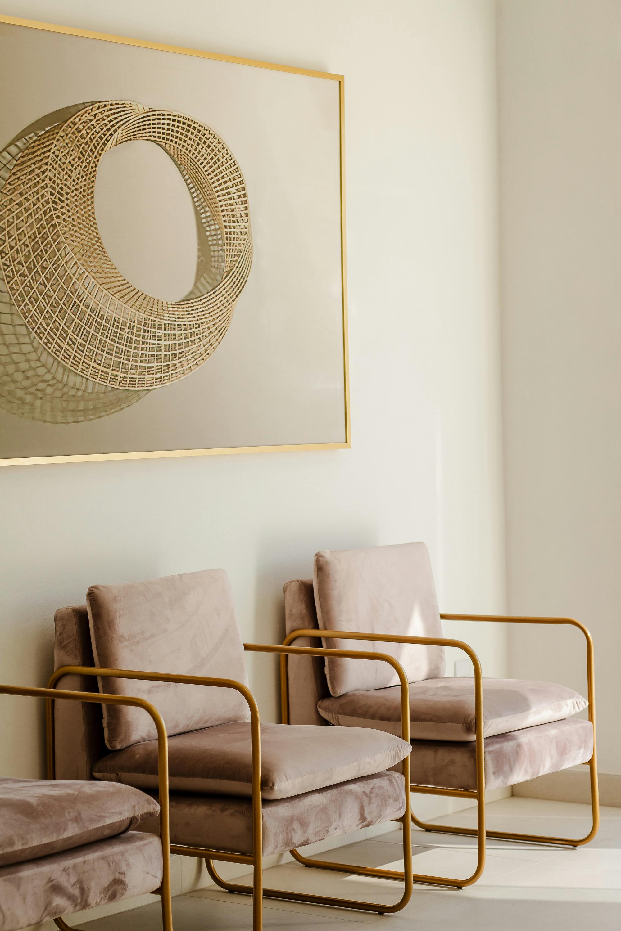 Stylish interior featuring modern artwork and plush armchairs with gold frames, creating a sophisticated space.