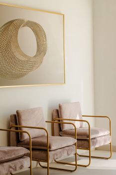 Stylish interior featuring modern artwork and plush armchairs with gold frames, creating a sophisticated space.