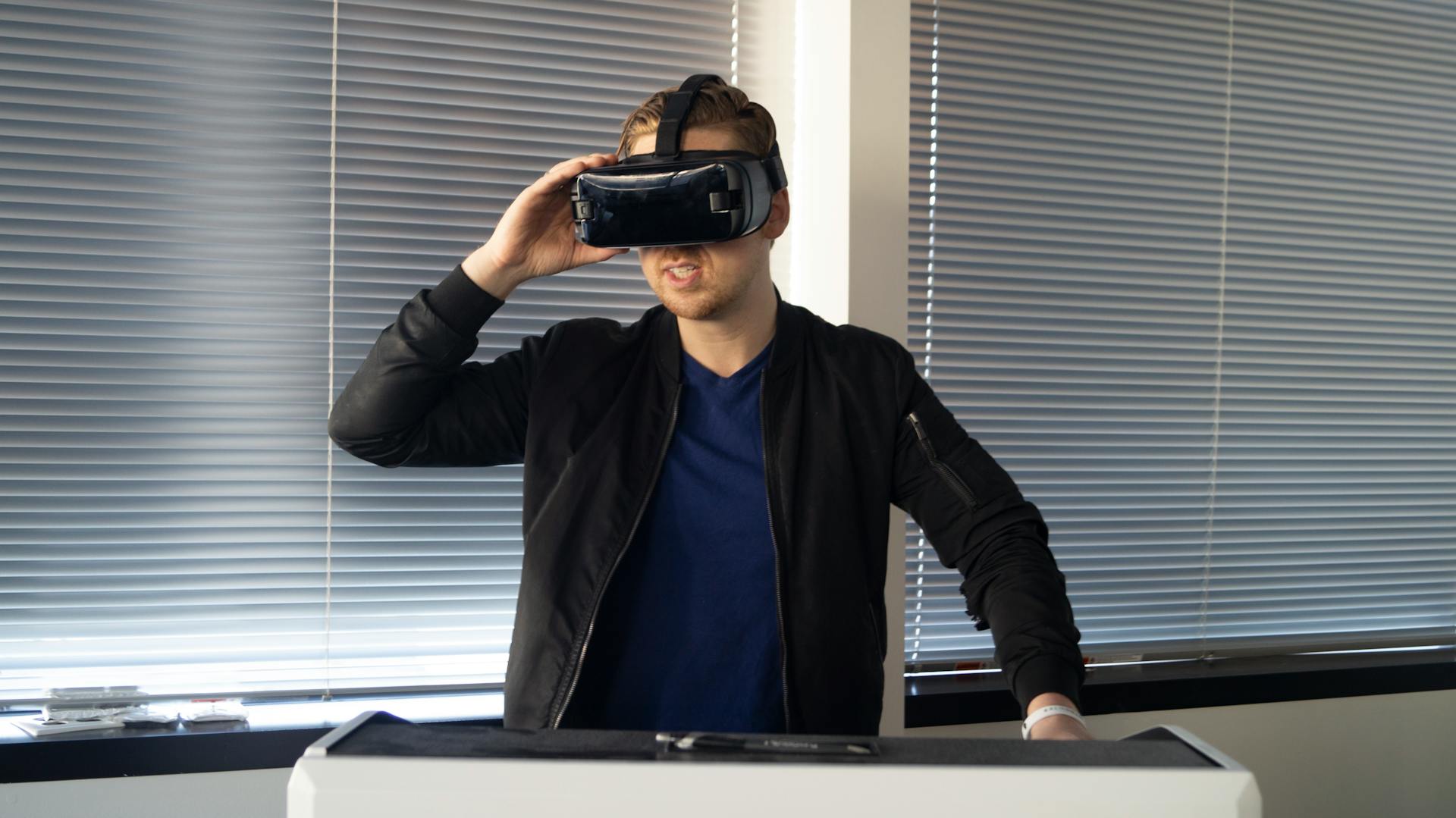 A young man immersed in a virtual reality experience indoors, using a VR headset.