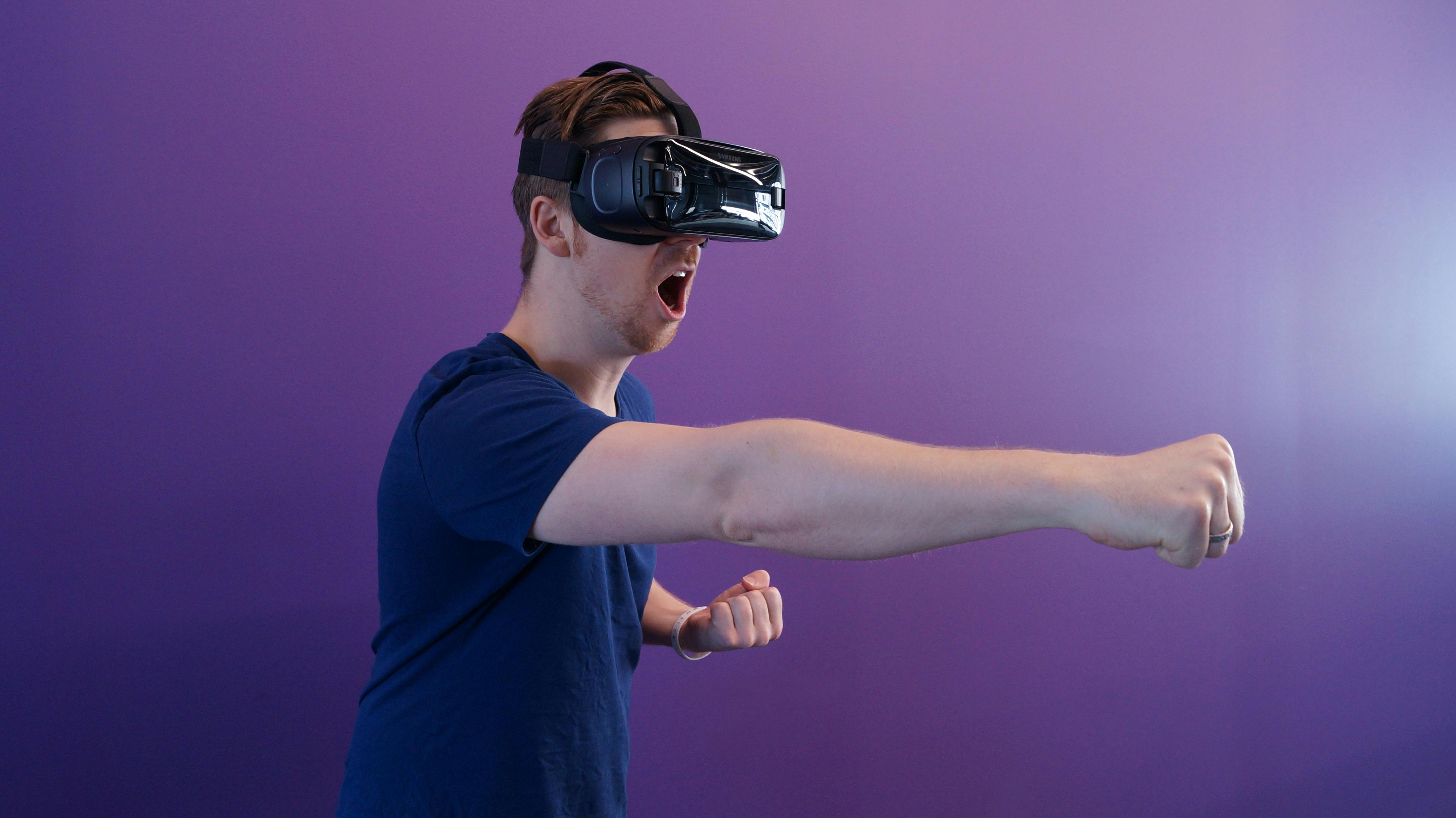 Man punching in the air while wearing VR goggles.