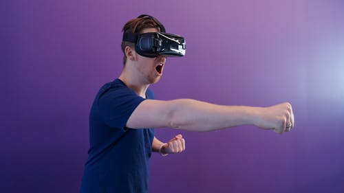 Free Man Punching in the Air while in VR Goggles Stock Photo
